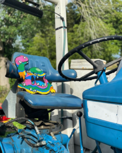 Pokémon Alolan Muk Perler bead artwork. Alolan Muk is positioned in the driver's seat of a blue tractor to look as if it is driving.